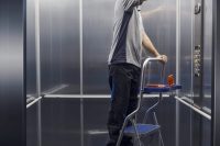 Professional elevator mechanic at work, he is checking and repairing the elevator