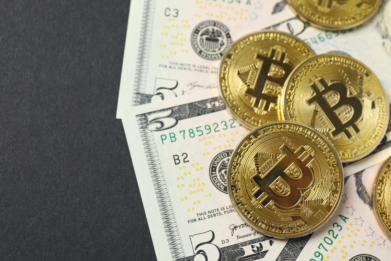 Golden metal shiny bitcoin crypto currency coins on US dollar bills. Electronic decentralized money concept. Top view