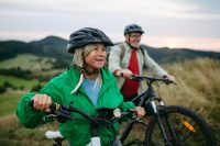 Older couple cycling together in nature, smiling and enjoying outdoor adventure.