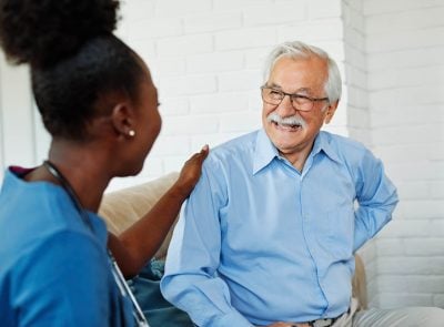 Portrait of a senior man with doctor or nurse caregiver at home or nursing home
