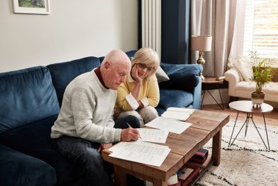Senior couple, retirement and writing documents of investment report, financial assets or sign legal contract of insurance policy. Man, woman and paperwork for budget, pension savings or loan at home