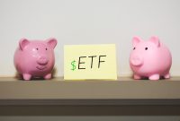 Exchange Traded Fund ETF initials written on a piece of paper with two piggy banks in the composition.