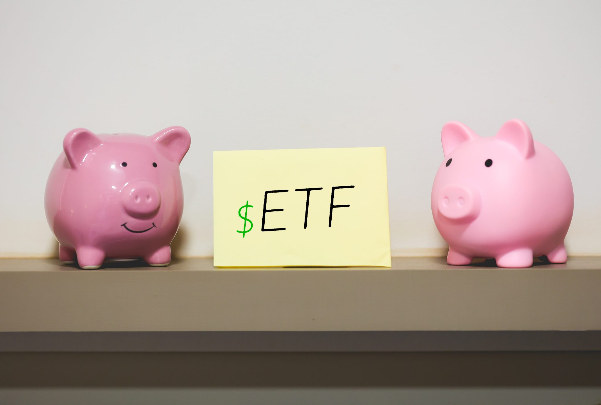 Exchange Traded Fund ETF initials written on a piece of paper with two piggy banks in the composition.
