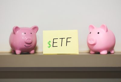 Exchange Traded Fund ETF initials written on a piece of paper with two piggy banks in the composition.