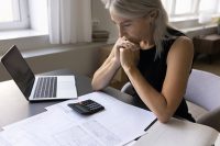 Serious old lady self employed businesswoman ponder on risky decision calculate possible income expenses. Small business owner focused on bookkeeping solve tax problem check bank accounts at workplace