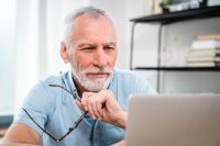 Happy smiling mature Caucasian business man ceo trader using computer, typing, working in modern office, doing online data market analysis, thinking planning tech strategy looking at laptop.