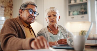 Laptop, finance and senior couple in home for budget, pension and mortgage payment. Retirement, taxes and man and woman with paperwork for life insurance, investment and bills for online banking