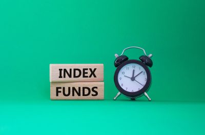 Index Funds symbol. Concept words Index Funds on wooden blocks. Beautiful green background with alarm clock. Business and Index Funds concept. Copy space.
