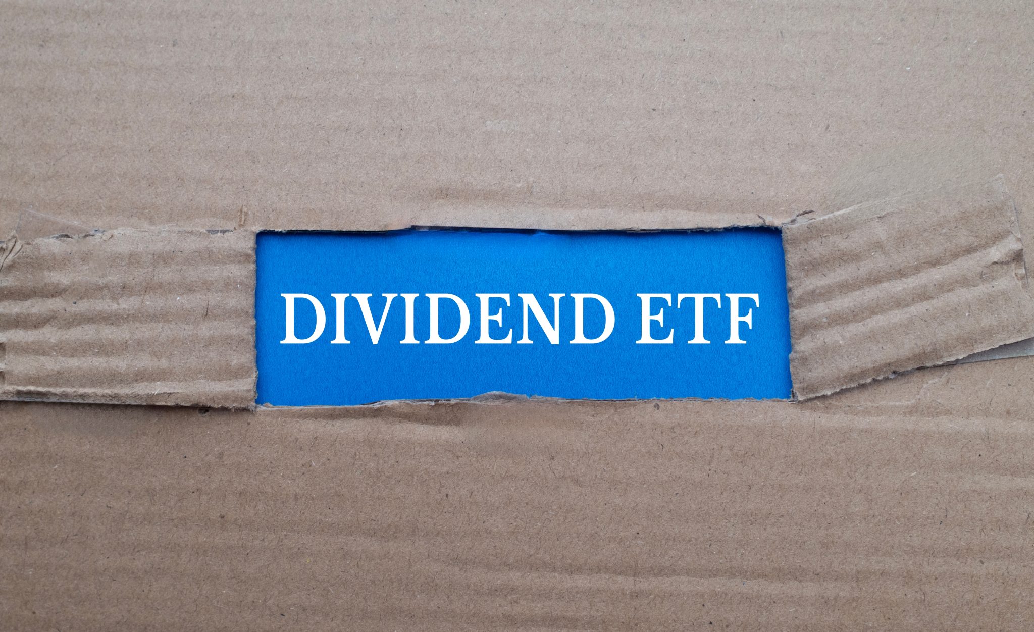 Dividend ETF text on blue paper over torn card box background