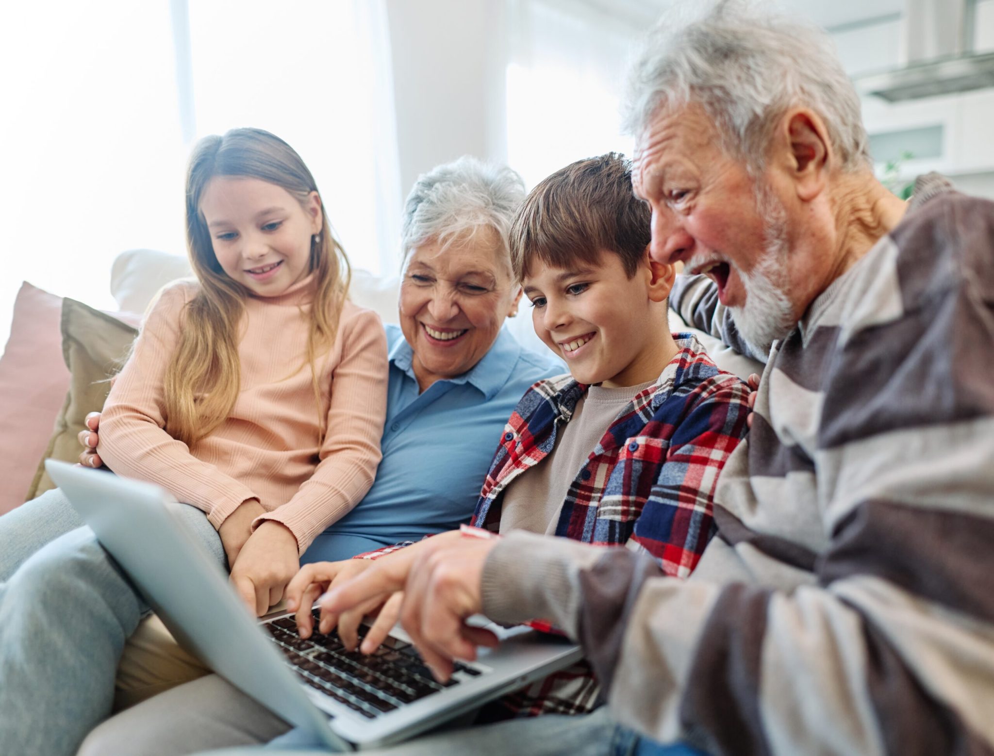 Family grandparents and grandchildren having fun at home using laptop